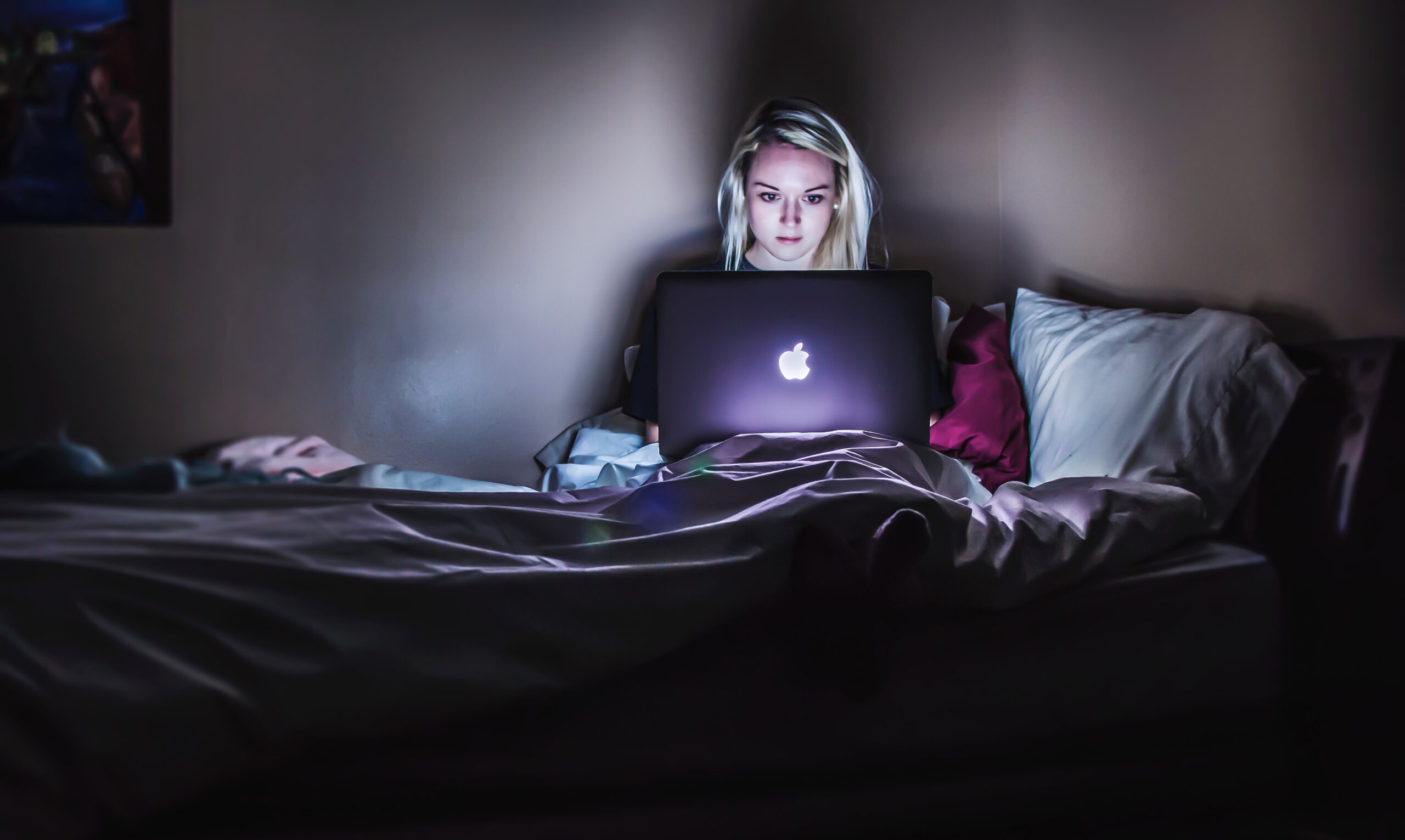 A person on their bed with a laptop