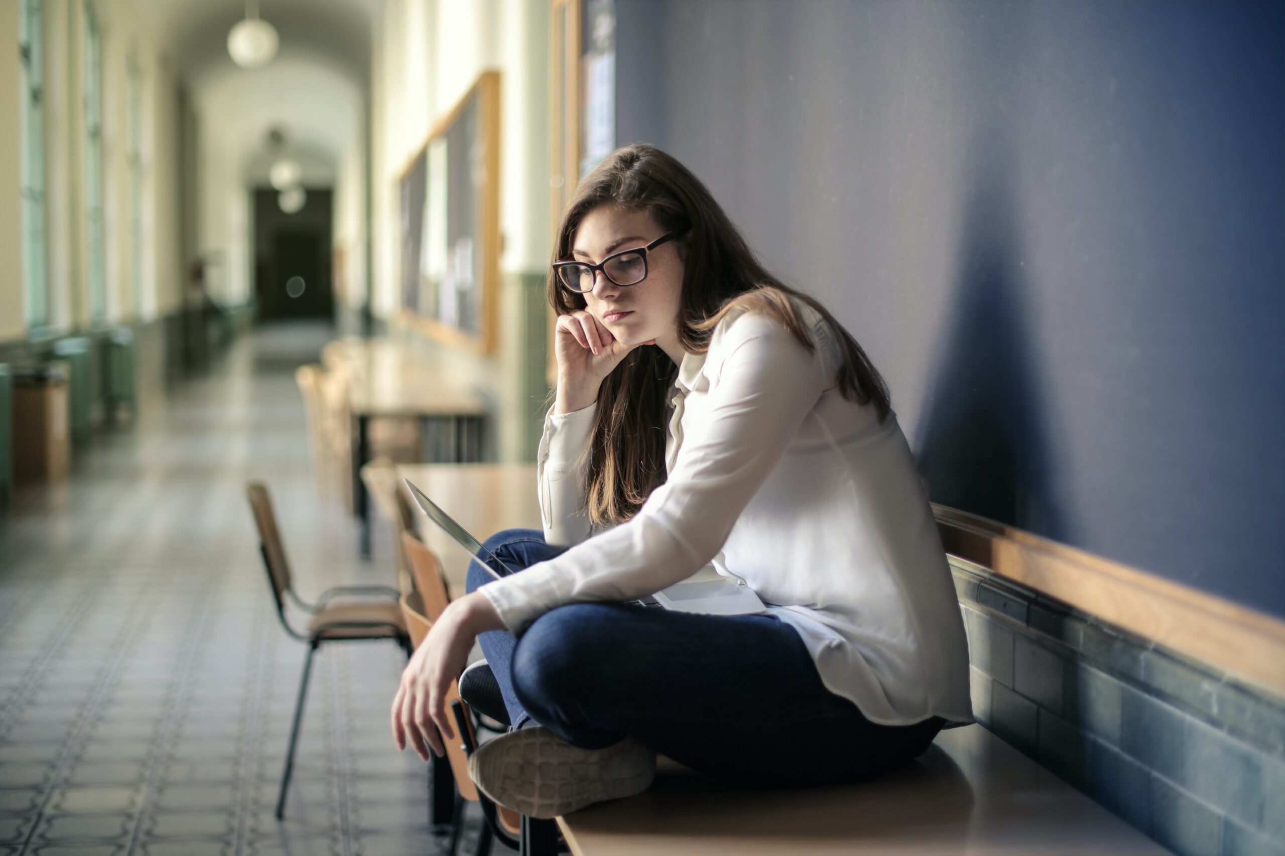 sad person sitting alone on bench in school hallway